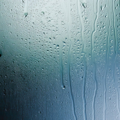 Water droplets running down condensation on glass.