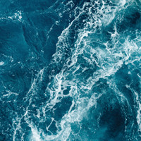 Top-down view of churning dark blue ocean water and white foam.